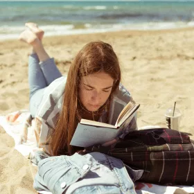 Donna che legge il libro sulla spiaggia durante il giorno