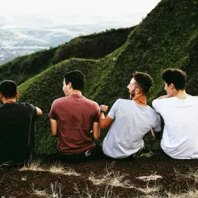 Quattro giovani seduti sul sentiero di montagna